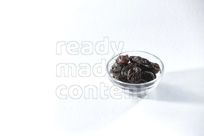 A glass bowl full of dried plums on a white background in different angles