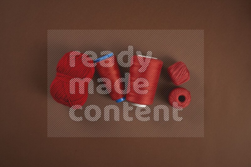 A red collection of sewing and tailoring tools arranged on a brown background
