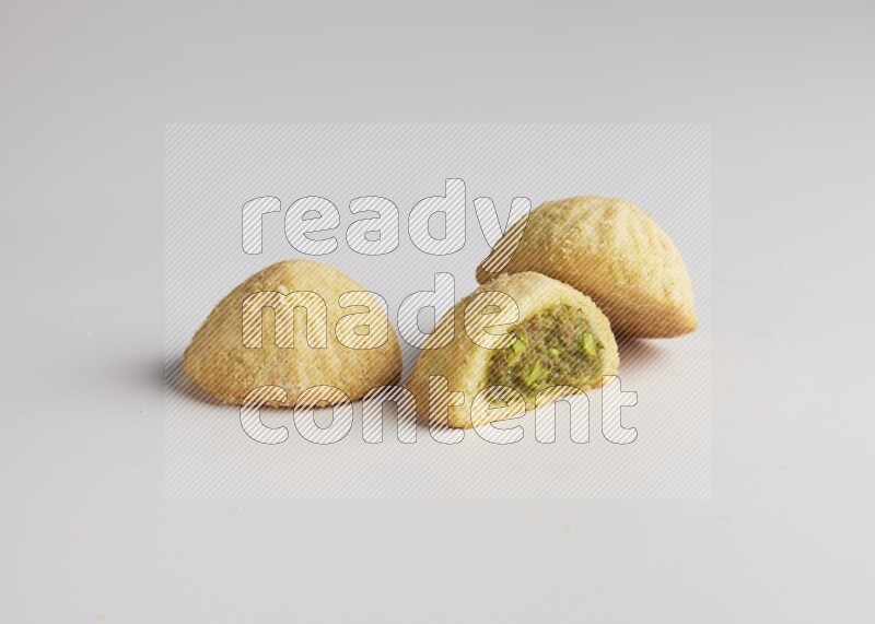 Three Pieces of Maamoul filled with pistachio paste  one of them is cut direct on white background