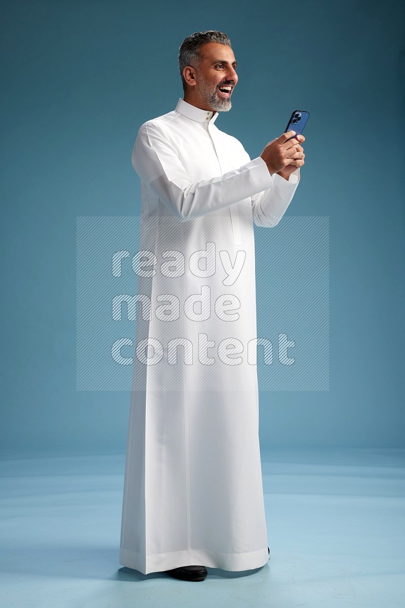 Saudi man waring thob texting on blue background