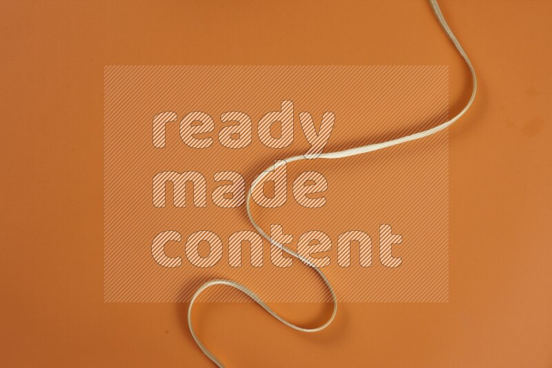 A green and orange collection of sewing and tailoring tools arranged on a orange background