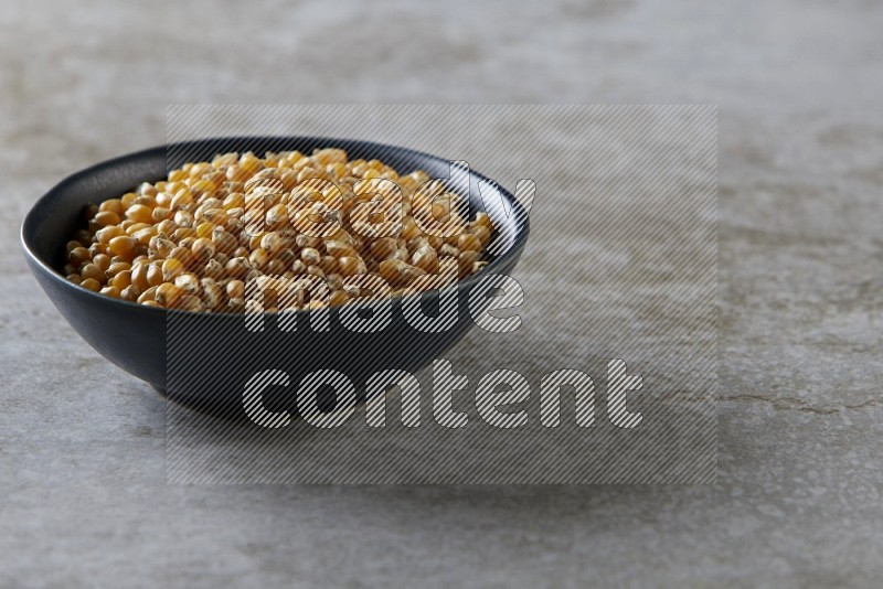 corn kernel in a black ceramic bowl on a grey textured countertop