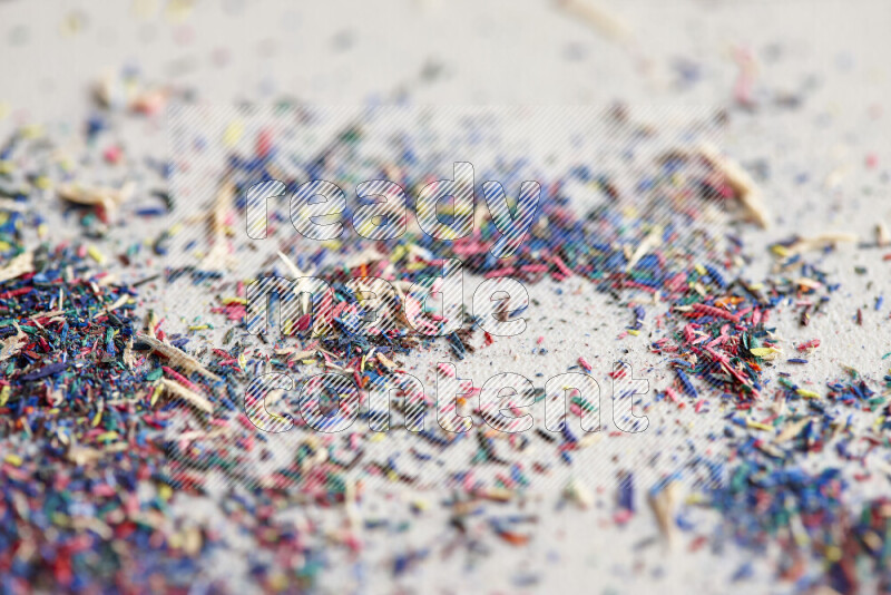 This image showcases a vibrant multicolored pencil shavings scattered on grey background