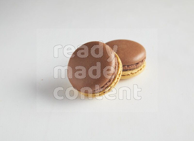 45º Shot of two Yellow and Brown Chai Latte macarons on white background
