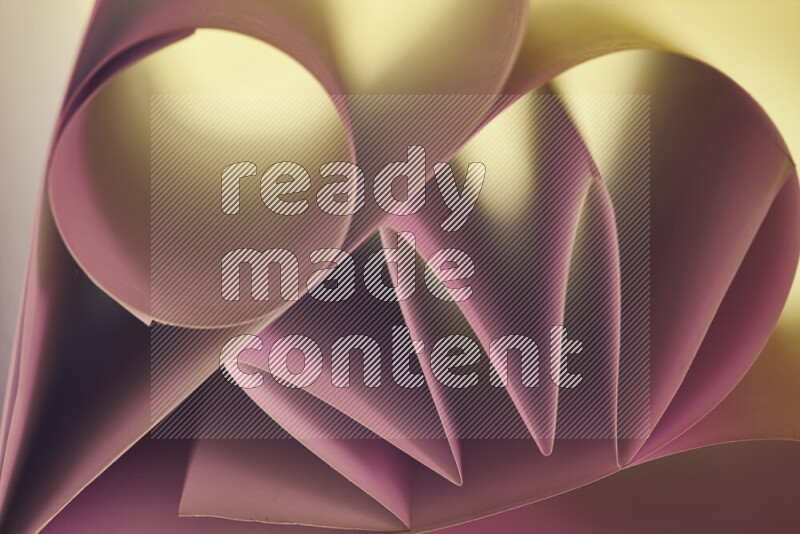 An artistic display of paper folds creating a harmonious blend of geometric shapes, highlighted by soft lighting in pink and warm tones