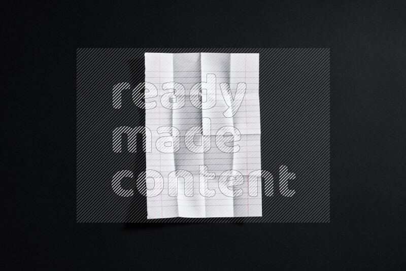 Folded notebook sheet on black background