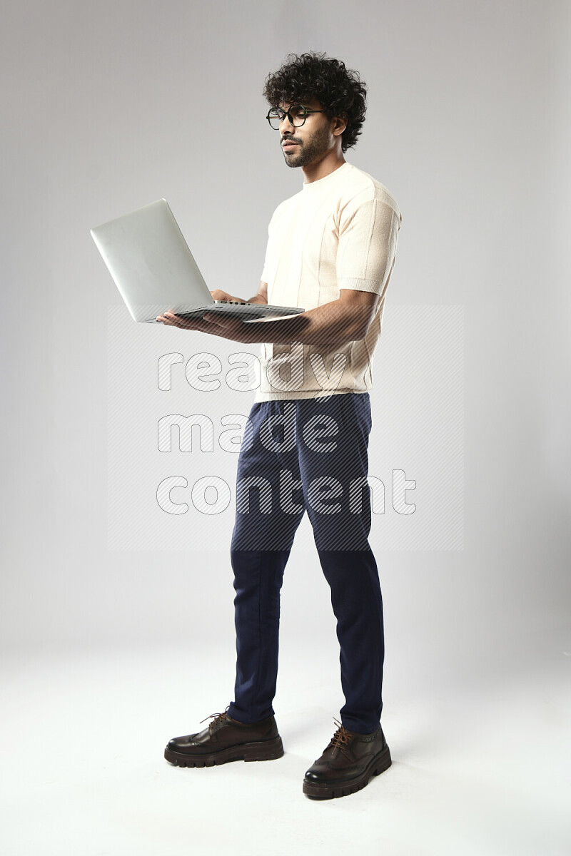 A man wearing casual standing and working on a laptop on white background