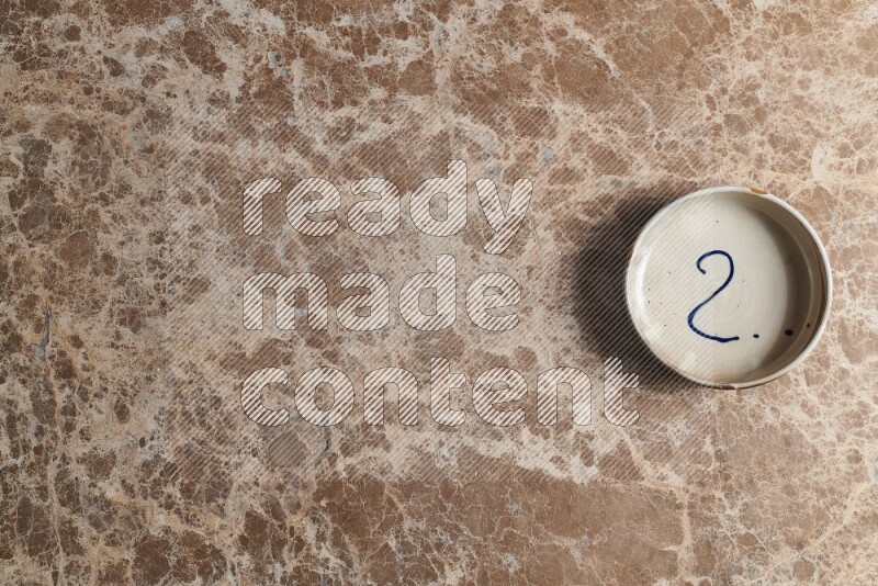 A multicolored pottery bowl on beige marble background