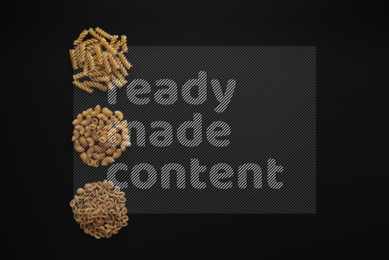 Different pasta types in 3 bunches on black background