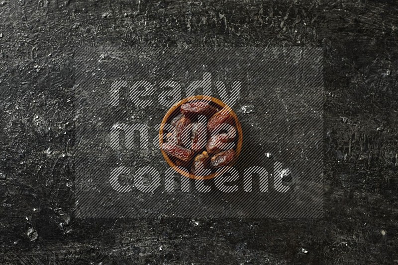 Dates in wooden bowls in a dark setup