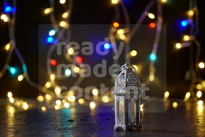 A white lantern with fairy light in a dark setup