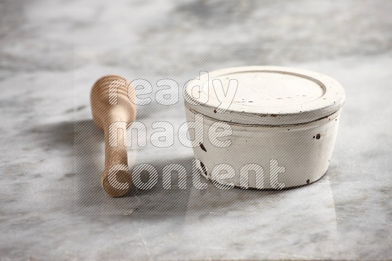 White Pottery Bowl with wooden honey handle on the side with grey marble flooring, 15 degree angle