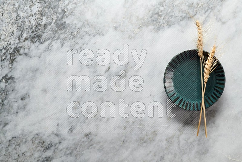 Wheat stalks on Multicolored Pottery Plate on grey marble flooring, Top view