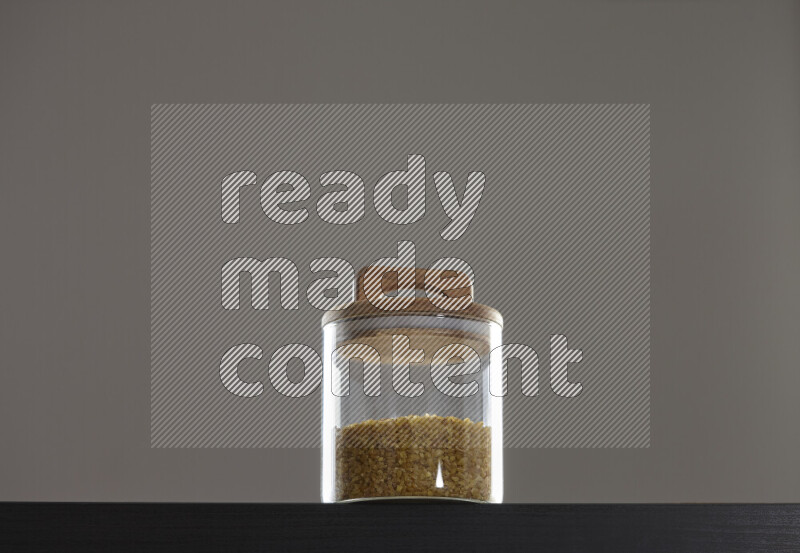 Coarse bulgur in a glass jar on black background