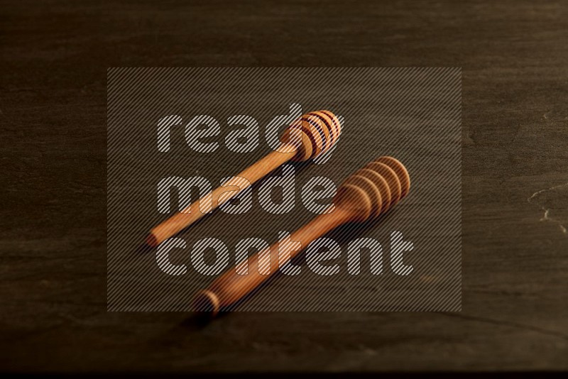 Wooden honey dipper on black slate background