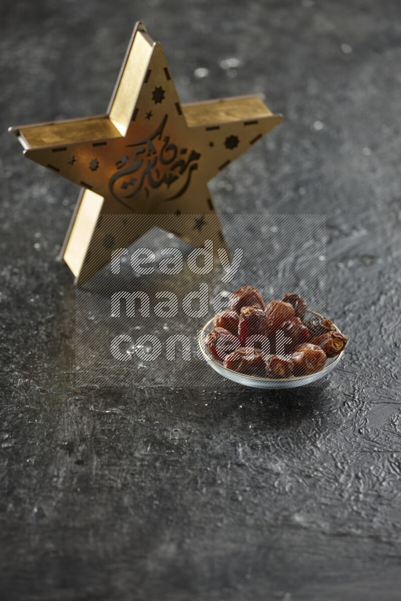 A wooden golden star lantern with different drinks, dates, nuts, prayer beads and quran on textured black background