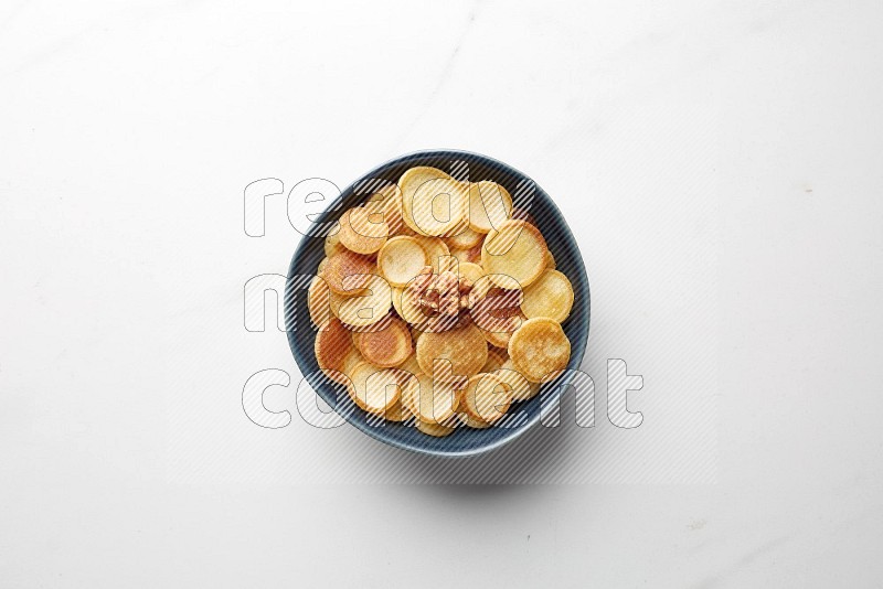 Top-view shot of walnut cereal pancakes in a round bowl on white background