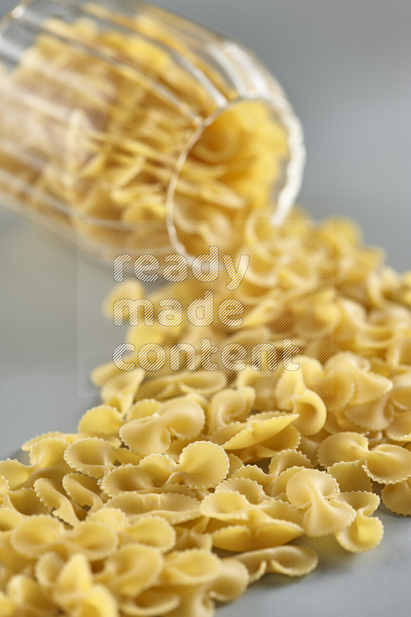 Flipped jar full of raw pasta on light blue background