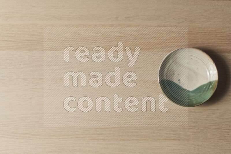 صحن فخاري متعدد الألوان على خلفية خشبية فاتحة