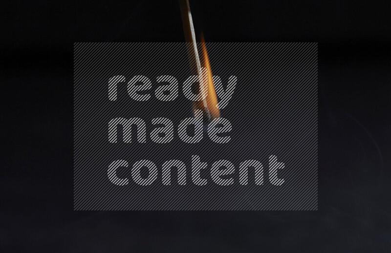 A burning matchstick isolated on dark backdrop