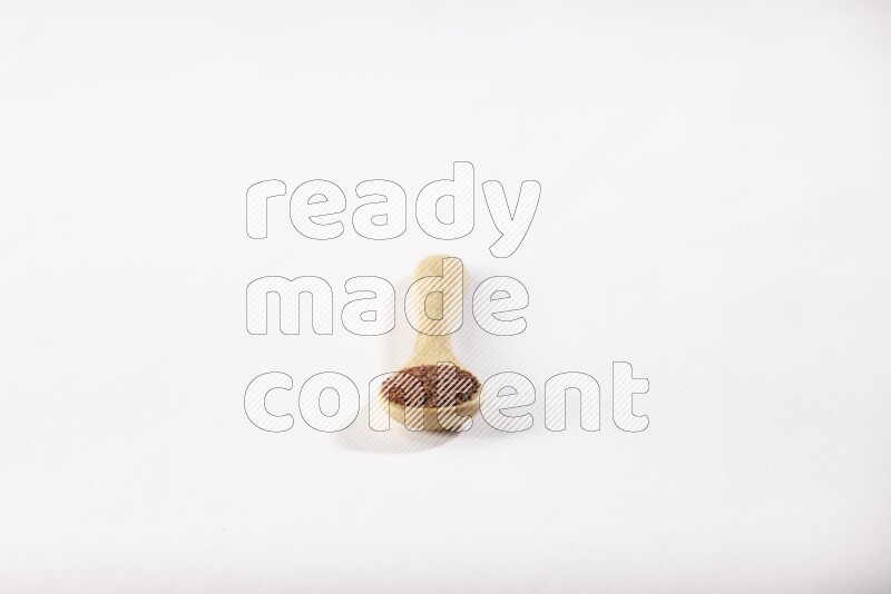 ملعقة خشبية ممتلئة ببذور حب الرشاد علي خلفية بيضاء