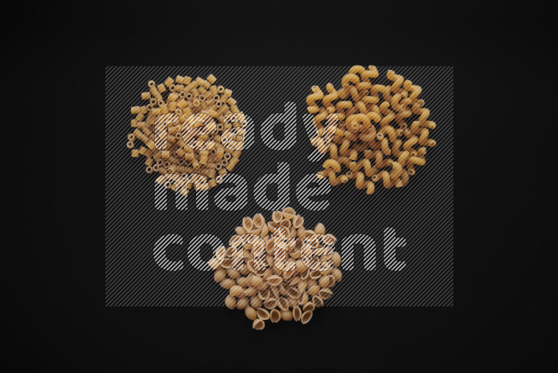 Different pasta types in bunches on black background