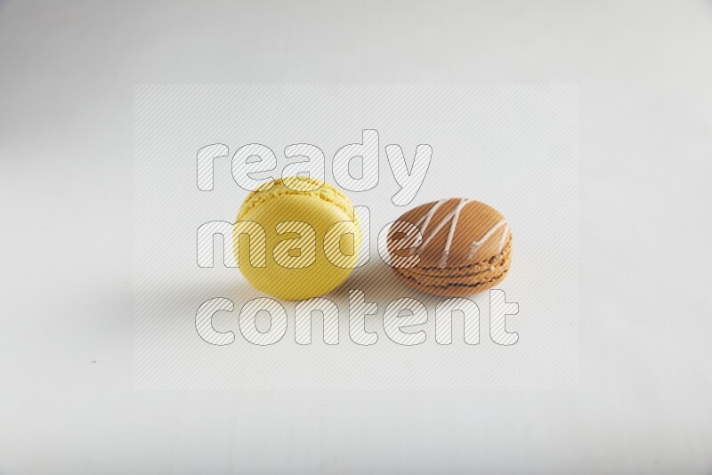 45º Shot of of two assorted Brown Irish Cream, and Yellow Lemon macarons on white background