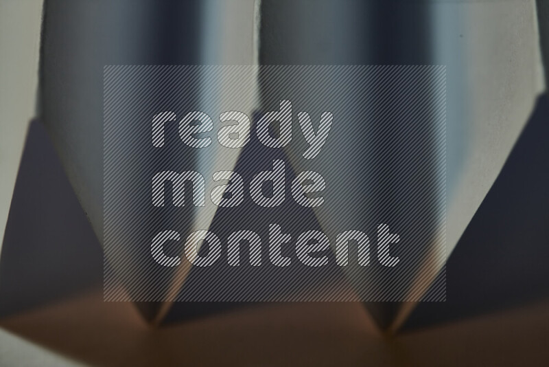 A close-up abstract image showing sharp geometric paper folds in blue gradients and warm tones