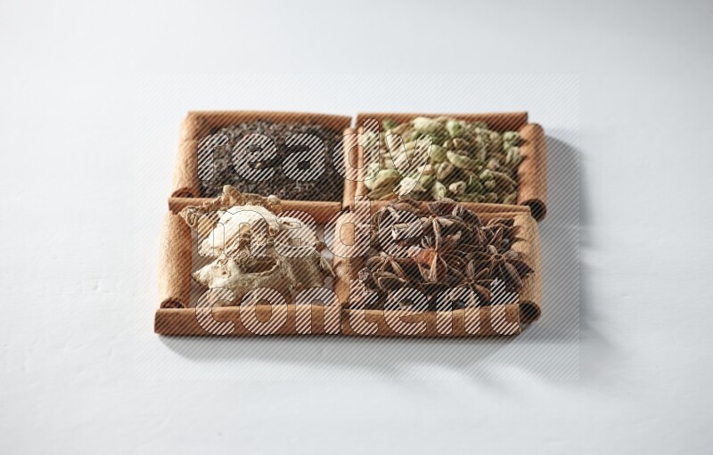 4 squares of cinnamon sticks full of tea, cardamom, star anise and ginger on white flooring