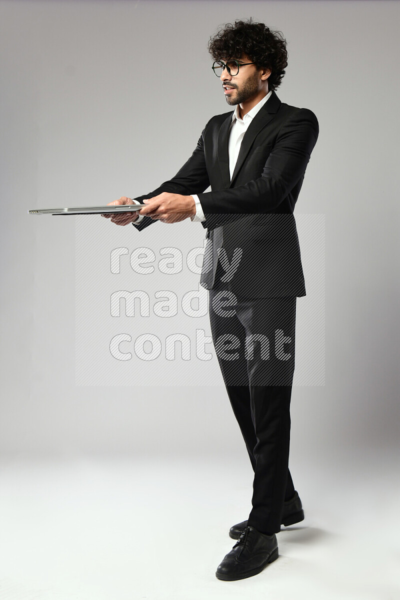 A man wearing formal standing and holding a laptop on white background