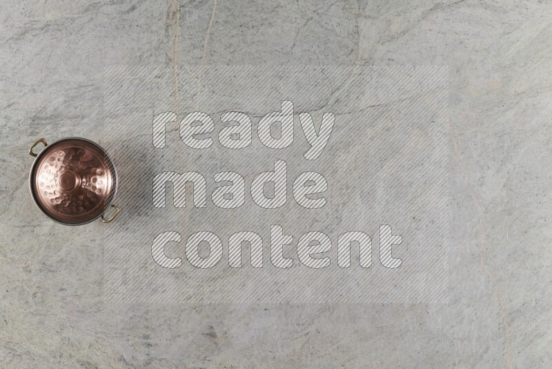 A small copper pot on grey marble background