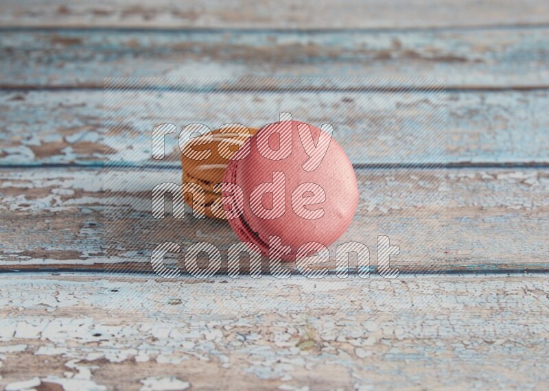 45º Shot of of two assorted Brown Irish Cream, and Pink Raspberry macarons on light blue background