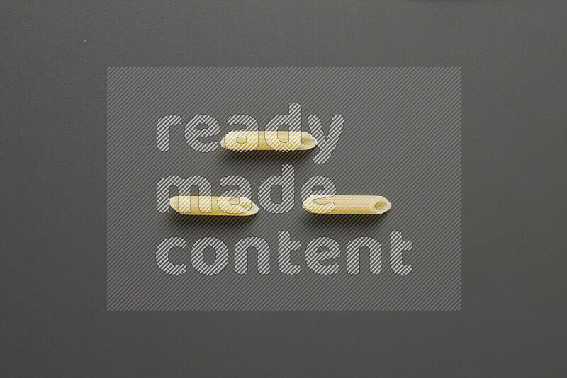 Mini penne pasta on grey background