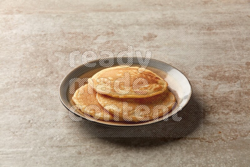 Three stacked plain pancakes in a bicolor plate on beige background