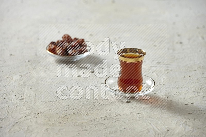 كوب زجاجي من الشاي مع التمر والقهوة على خلفية بيضاء