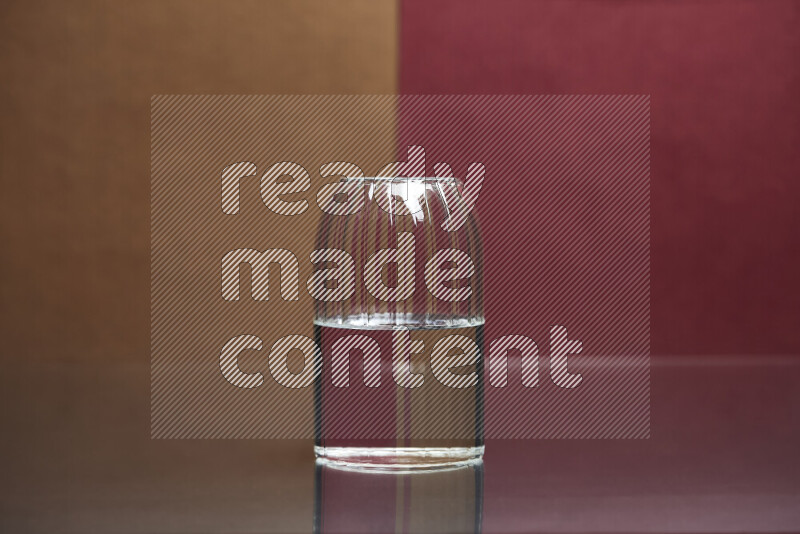 The image features a clear glassware filled with water, set against brown and dark red background