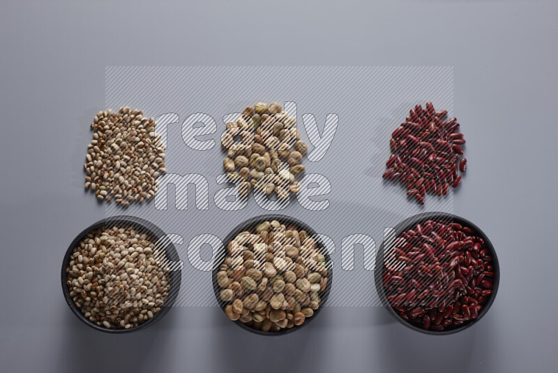 Legumes in pottery bowls on light grey background