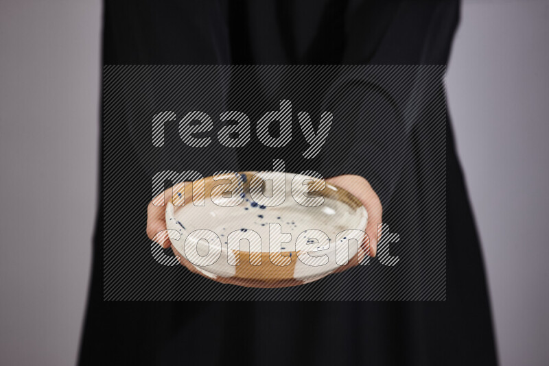 A woman in black abaya holding different pottery essentials in different positions