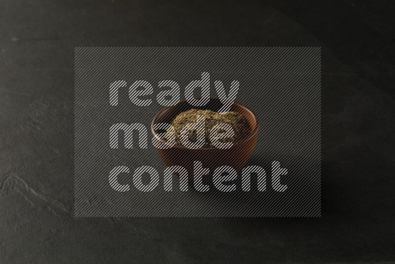 wooden round sauce bowl filled with herbs on grey textured countertop