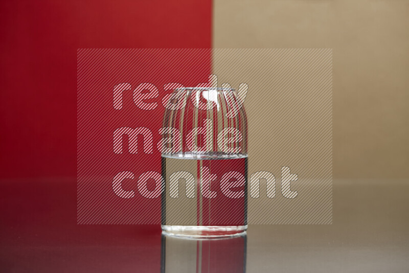 The image features a clear glassware filled with water, set against red and beige background