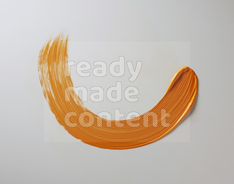 An orange half circular painting brush stroke on white background