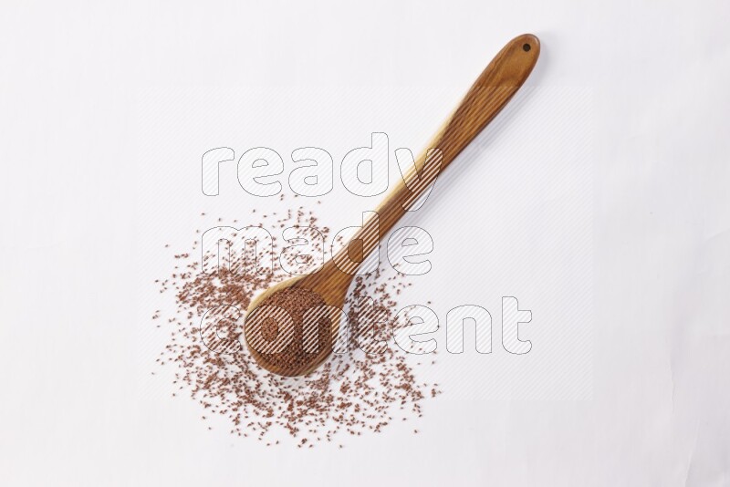 A wooden ladle full of garden cress seeds on a white flooring