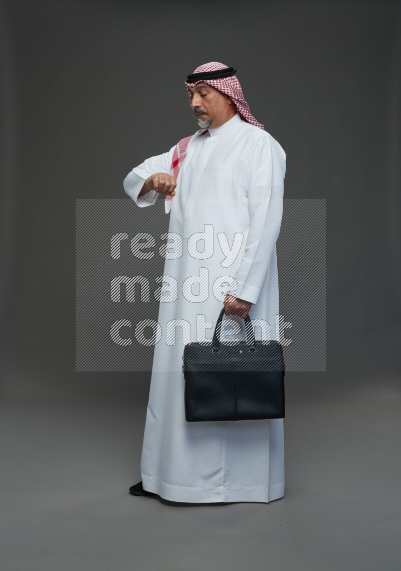 Saudi man with shomag Standing holding bag on gray background