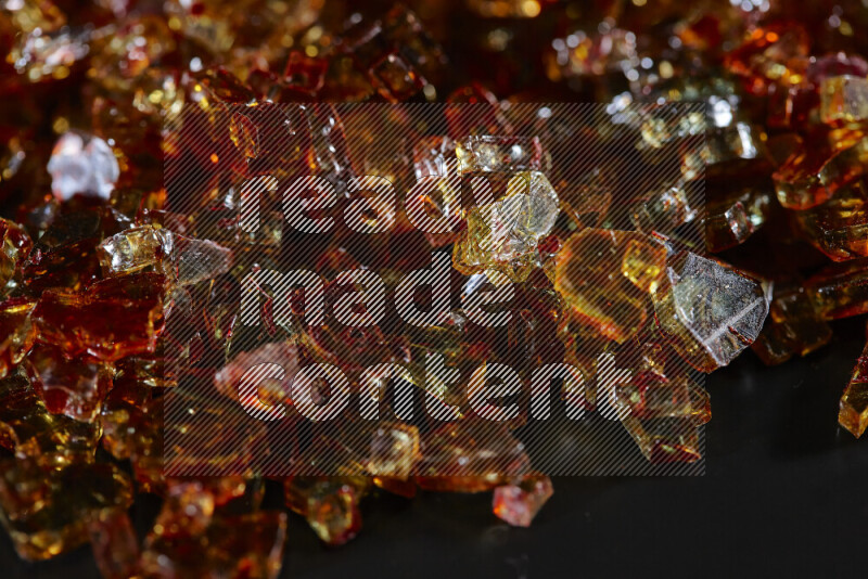 قطع زجاج برتقالية شفافة متناثرة على خلفية سوداء