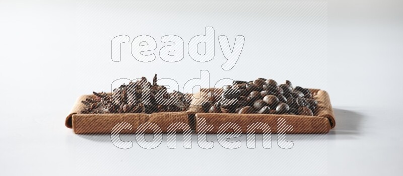 مربعان من أعواد القرفة ممتلئان بحبوب القهوة والقرنفل علي خلفية بيضاء