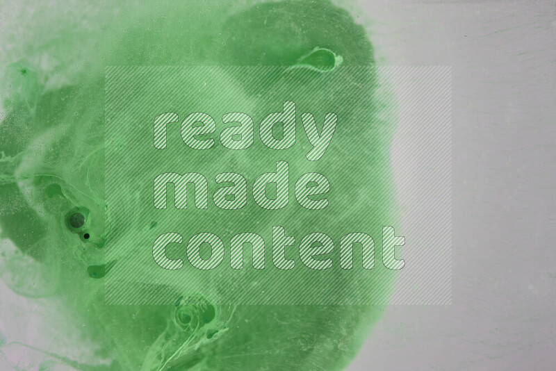 The image captures a dramatic splatter of green paint over a white backdrop