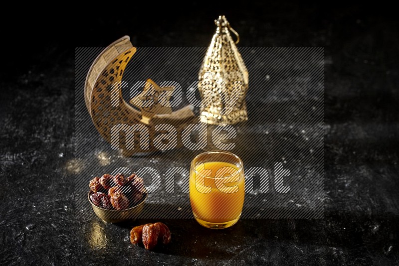Dates in a metal bowl with qamar el din beside golden lanterns in a dark setup