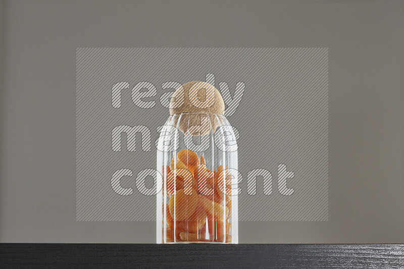 Dried apricots in a glass jar on black background