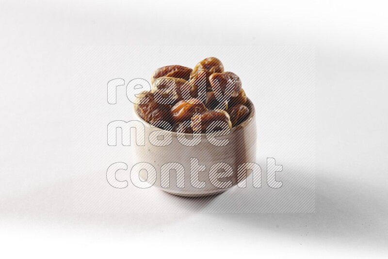 Dates in a beige pottery bowl on white background