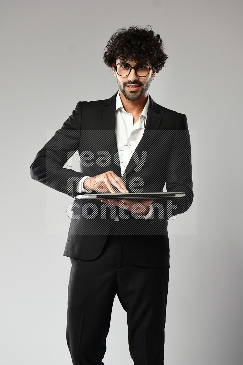 A man wearing formal standing and holding a laptop on white background